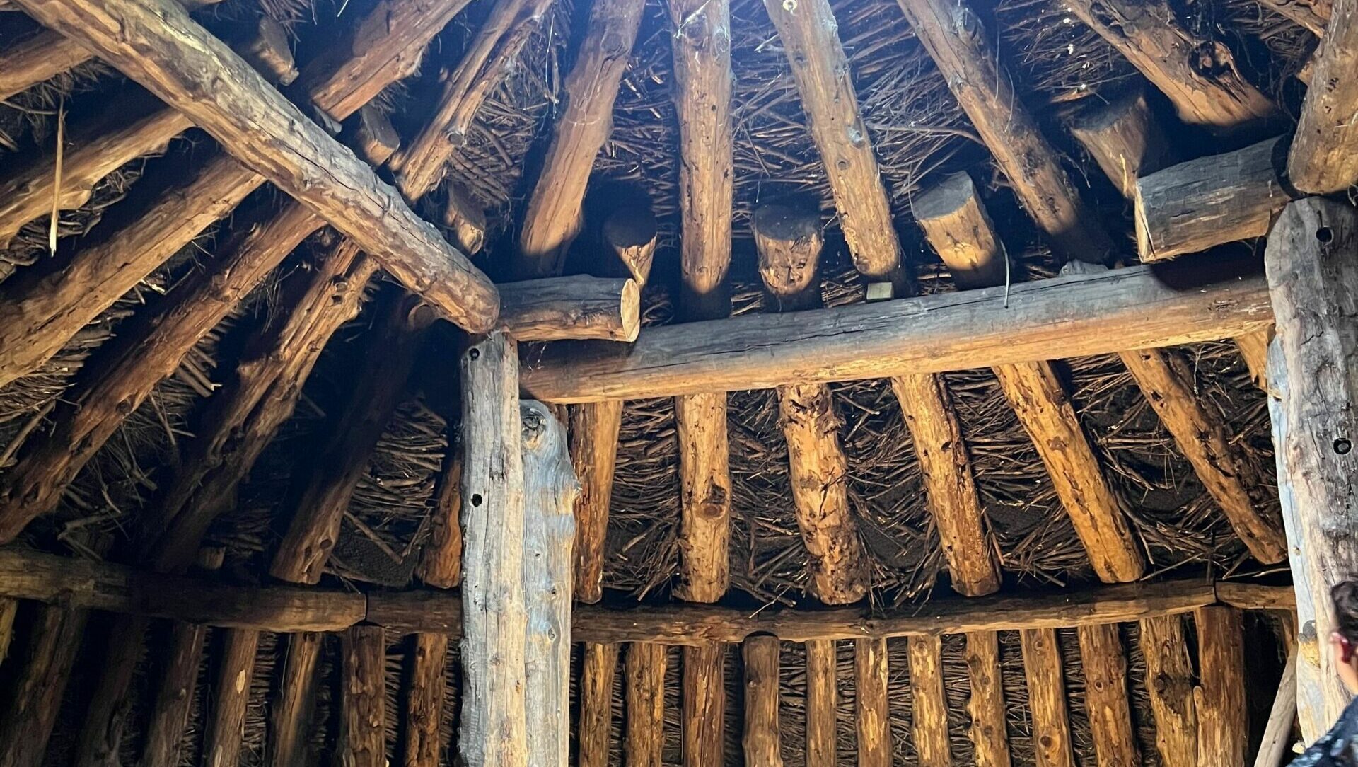 Interior of earth lodge showing wooden beams on the walls and roof.